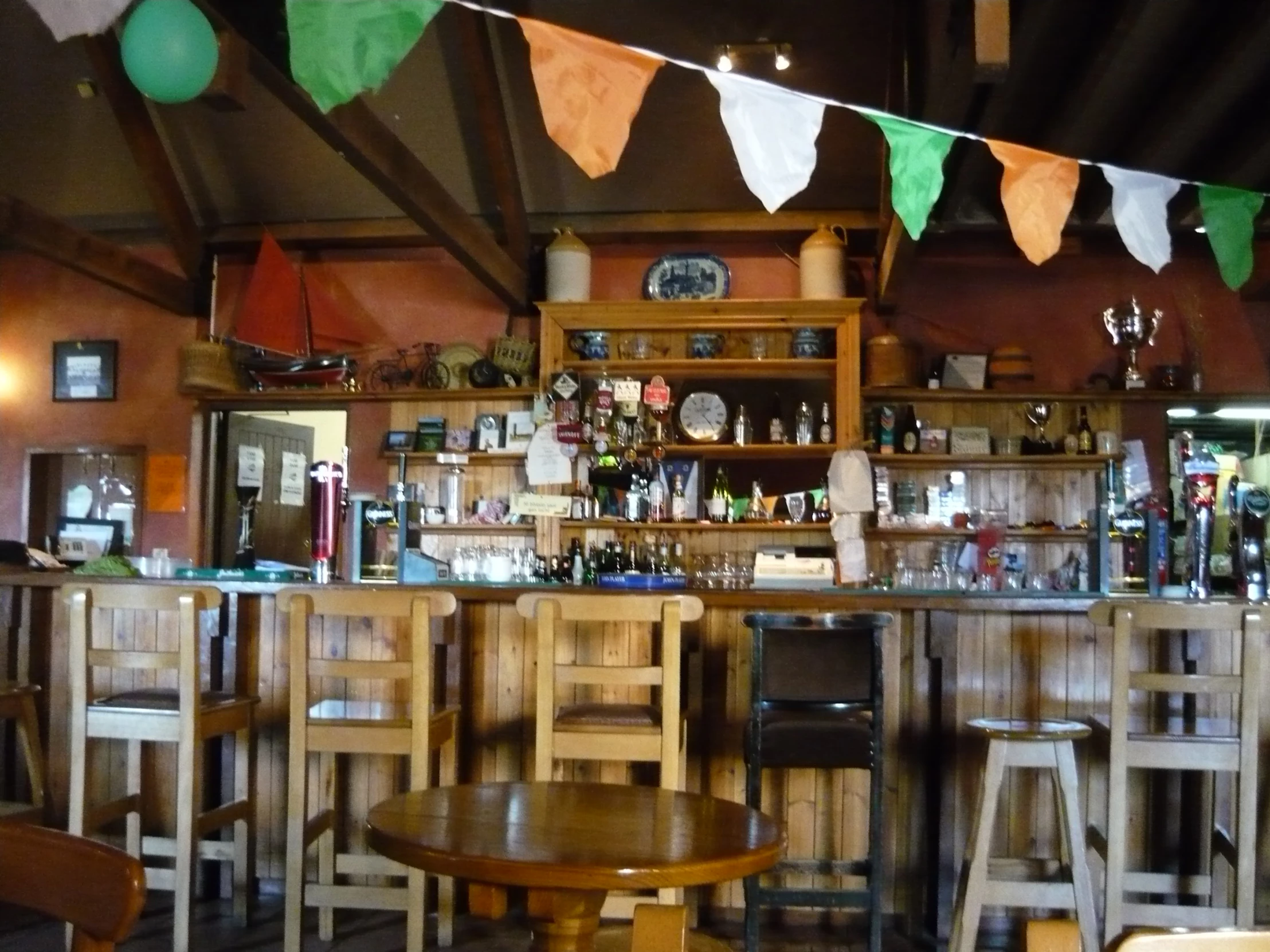 a bar that has some stools and green, orange and white flags