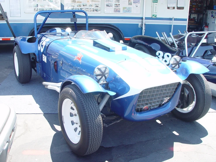 an older blue race car in front of a bus