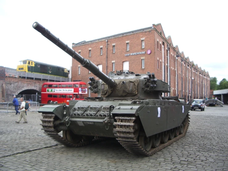 a tank is on display near a red bus