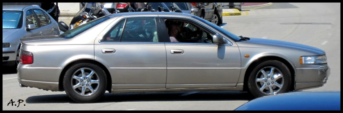 there is a silver car parked near motorcycles