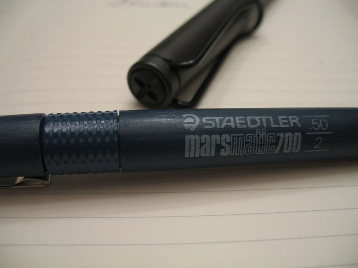 a black pen sitting on top of an open spiral bound notebook