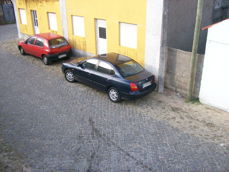 two cars are parked next to each other on a brick road