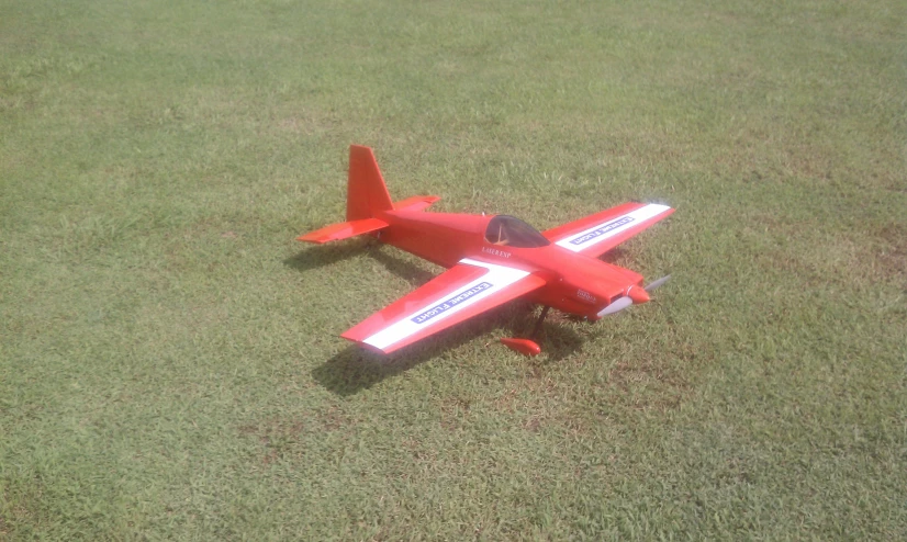 a red toy airplane sitting on the green grass