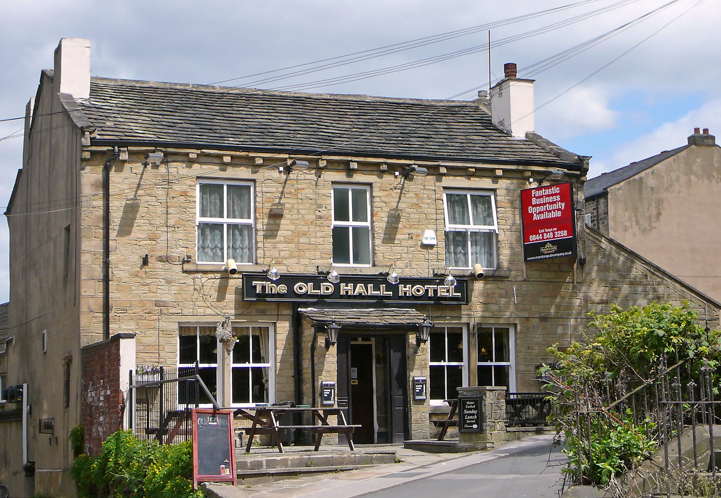 a street corner in front of a stone building with a business sign above it