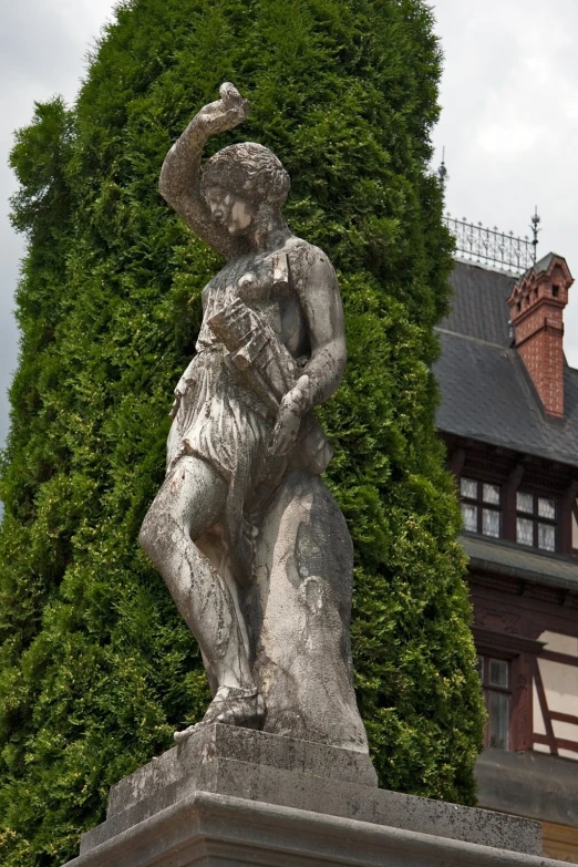 a tall tree is near the statue of a man holding a baby