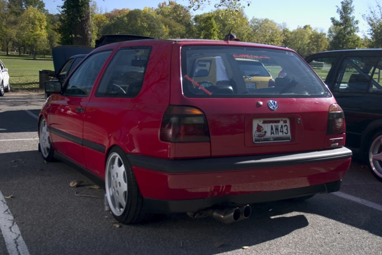 a red vehicle in a parking lot filled with cars