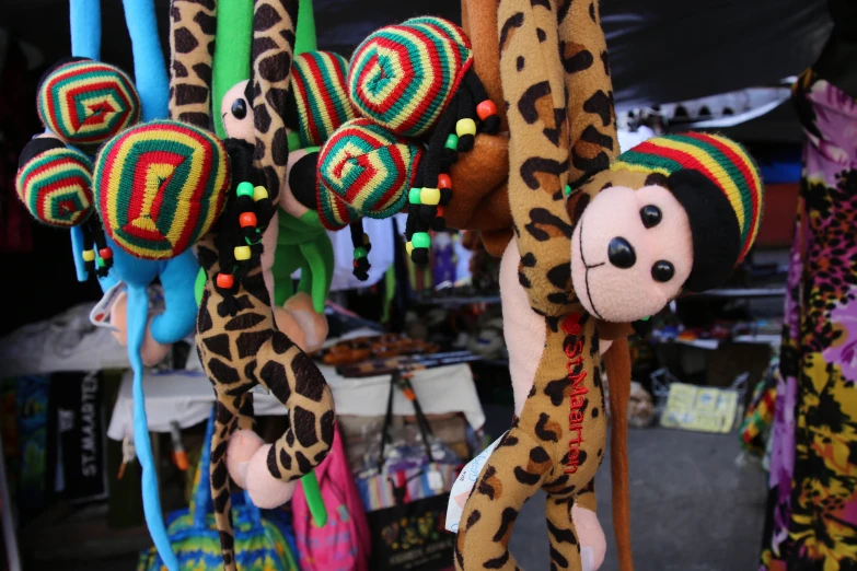 stuffed animals hanging from hooks at an outdoor market