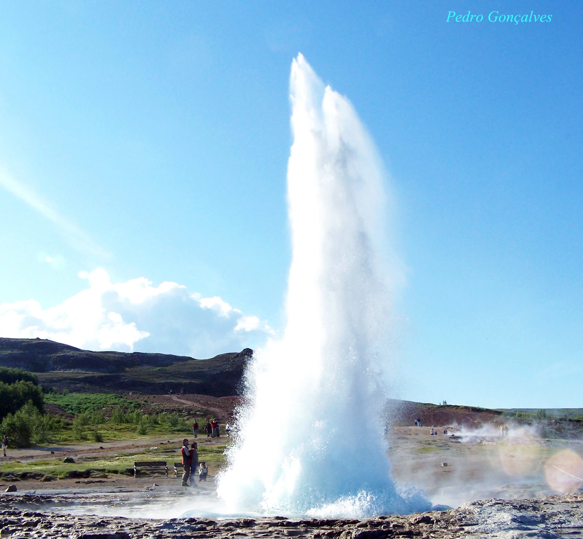 water shoots from an old geyser near a rural area