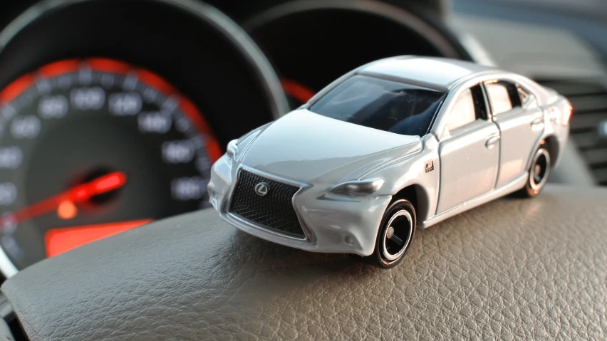 small toy car in front of steering wheel dashboard