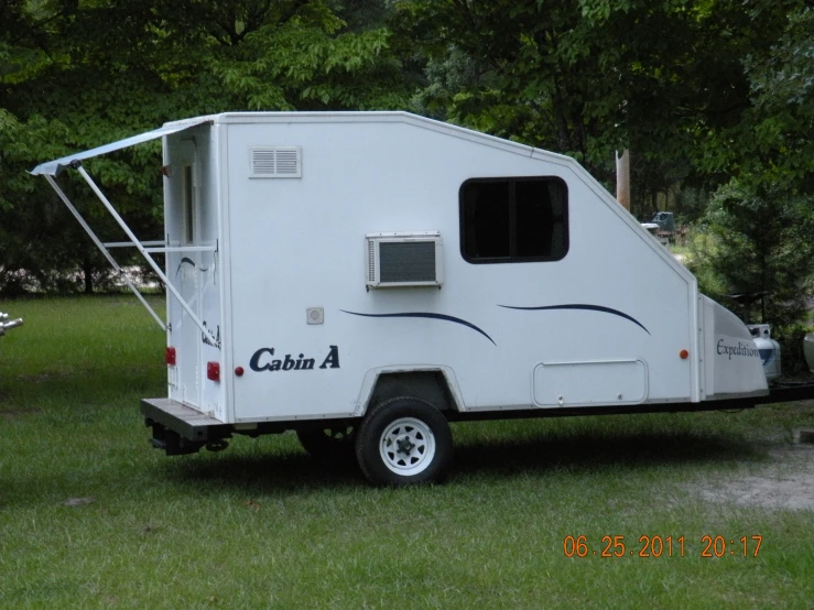 a white trailer is parked on a grassy field