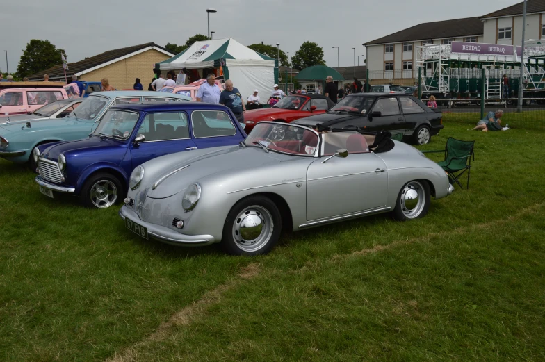 some antique cars parked in the grass near other vehicles