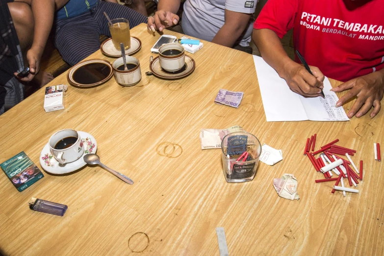 people around a table that is littered with tea and matches