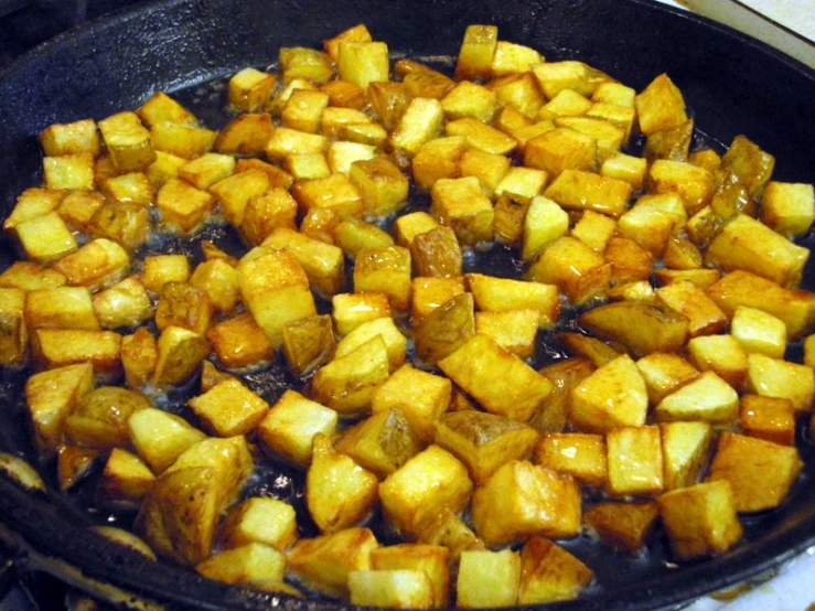 a pan full of potatoes cooking in oil