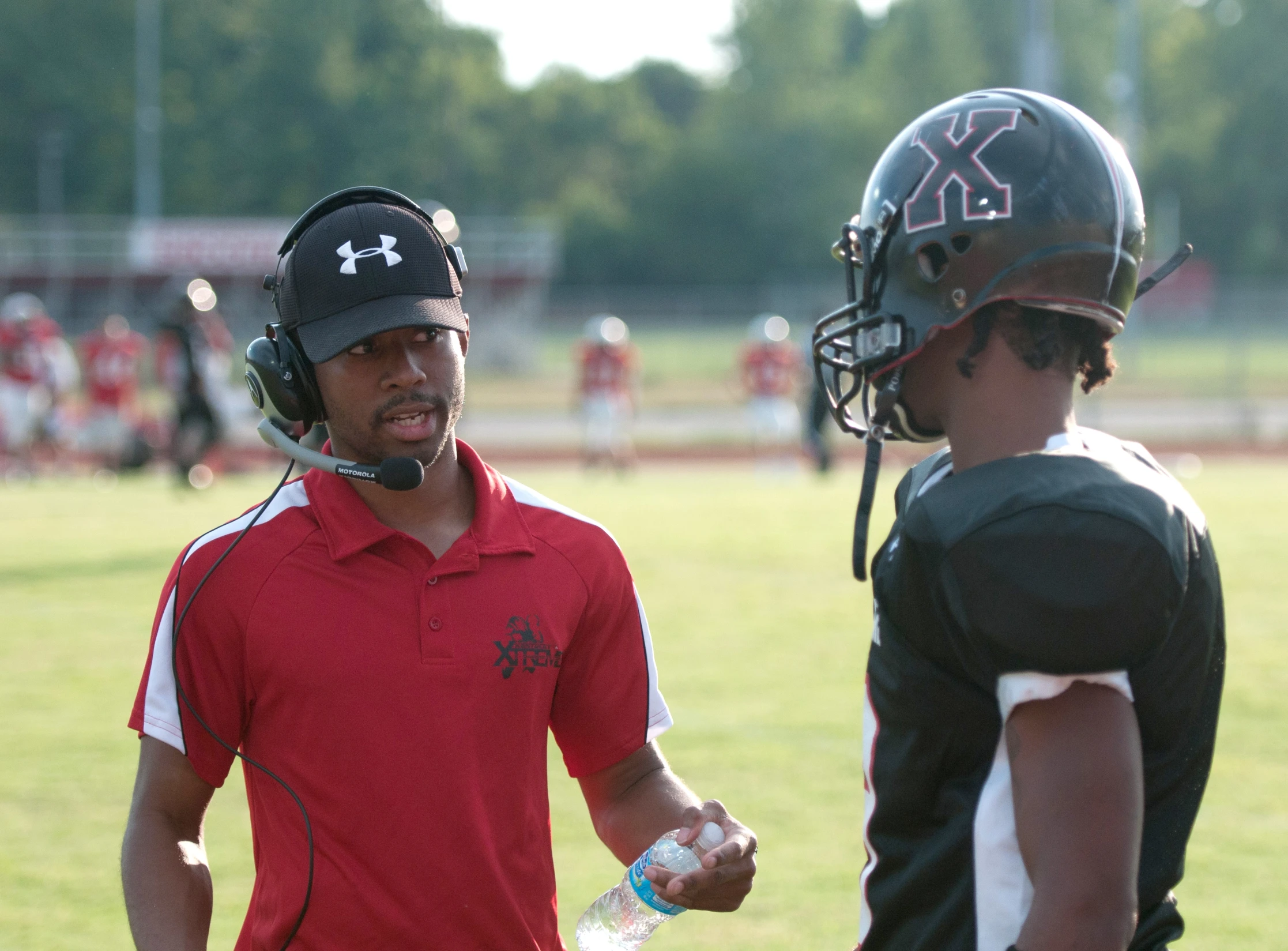 two young men are on the field with helmet and water bottles