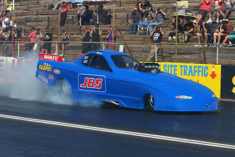 a very blue race car turning a corner in a drag