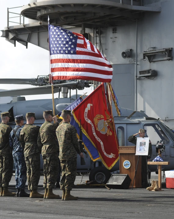 four military personnel with one man holding an american flag