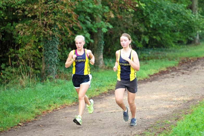 two women on a path run along the woods