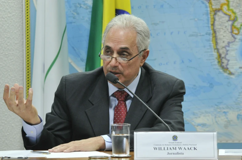 a man in a business suit is sitting at a table and talking