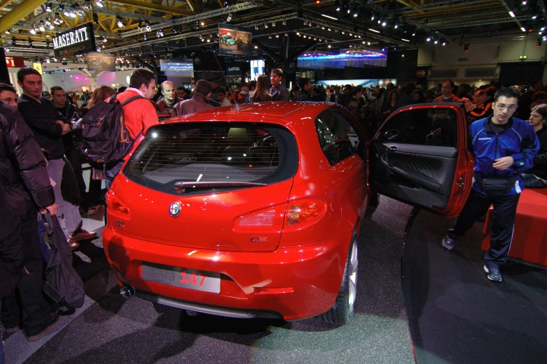 many people are standing around looking at a car on display