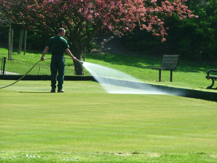 the man is watering the lawn with the hose