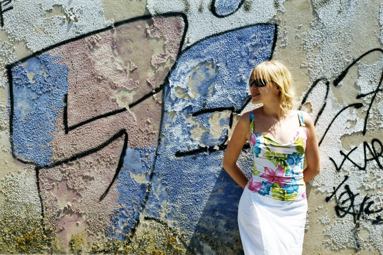 the woman poses by a graffiti covered wall