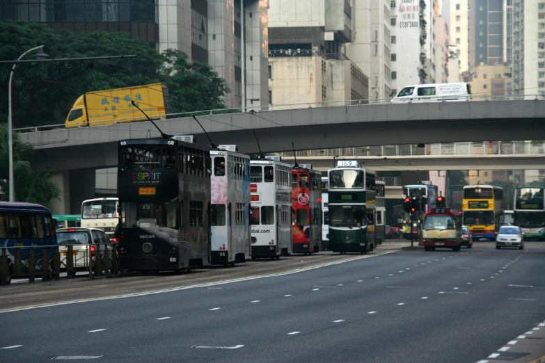 city buses are driving under a bridge, during the day