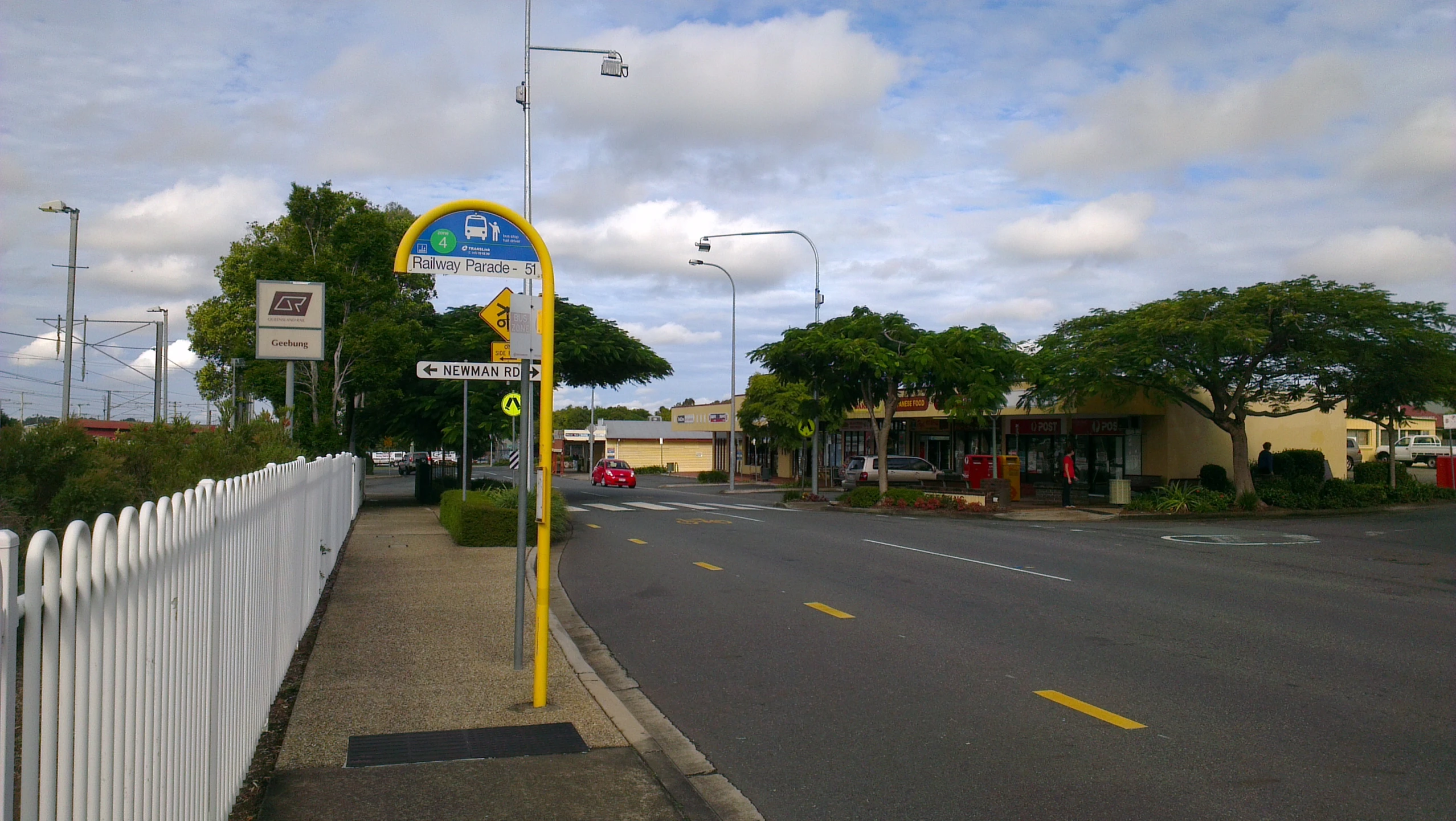 a road near a parking lot with white fences and trees