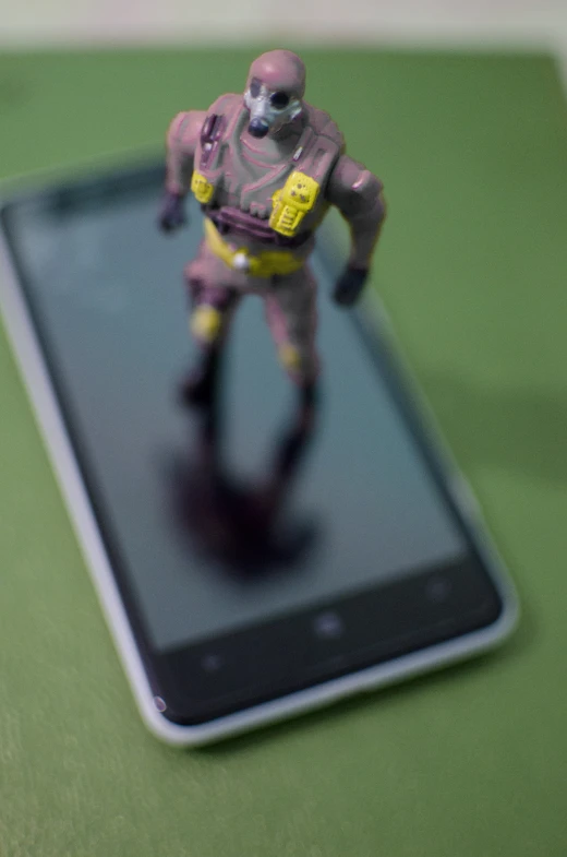 this robot toy is standing on a cellphone