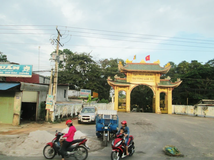 two motorcycles parked beside a small arch with a woman on the back of it