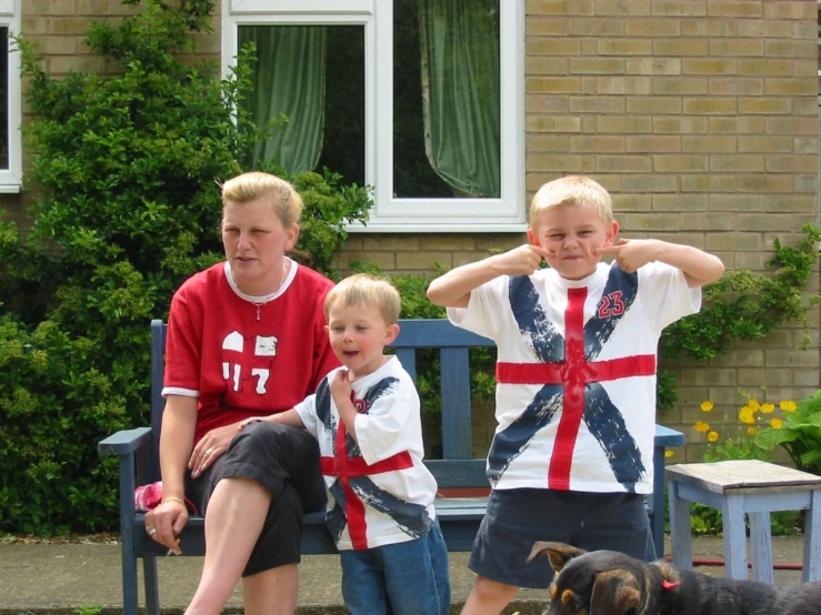 two boys and one dog sitting on a bench