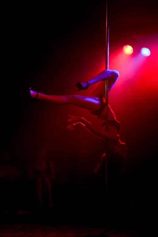 a woman doing a trick on a pole in the dark