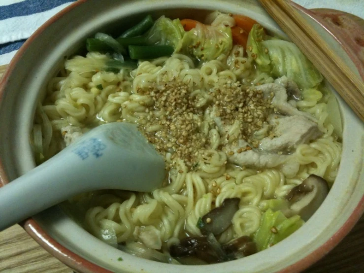 a bowl filled with noodles and vegetables on a wooden table