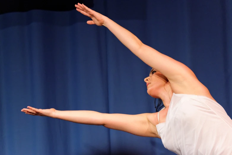 a young lady on a stage in white holding her hand up