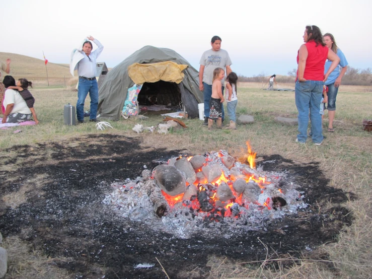 some people by a fire and an outdoor tent