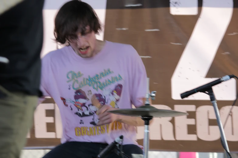 a boy in front of a microphone and singing on a drum kit