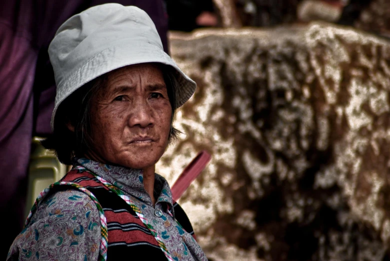 an asian woman in white hat sitting and looking at soing