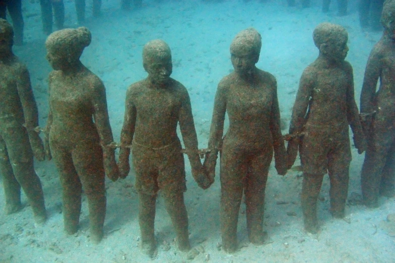 seven brown statues with white skin hold hands
