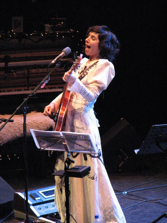 a woman in white holding onto her guitar