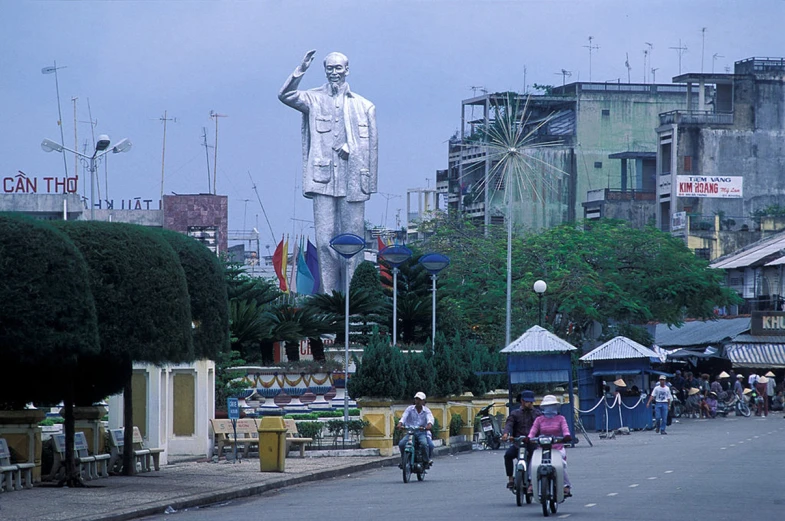 the people are riding their bikes past a statue