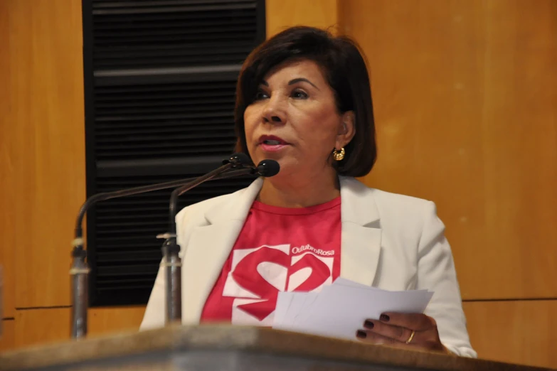 a woman stands before a microphone and speaks