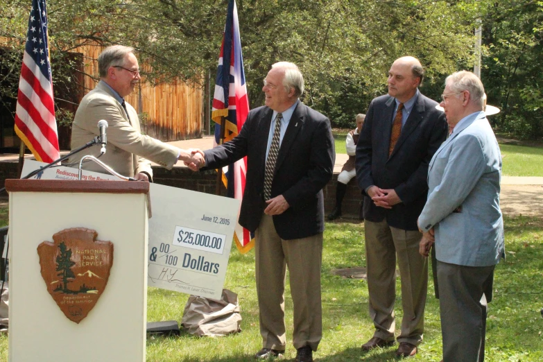 four men standing in front of a podium that has an american flag