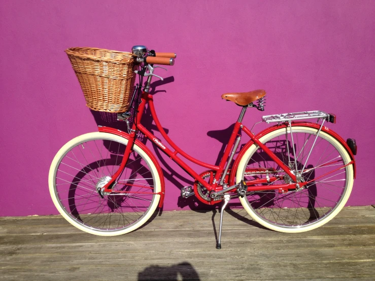 a red bicycle is parked by a purple wall