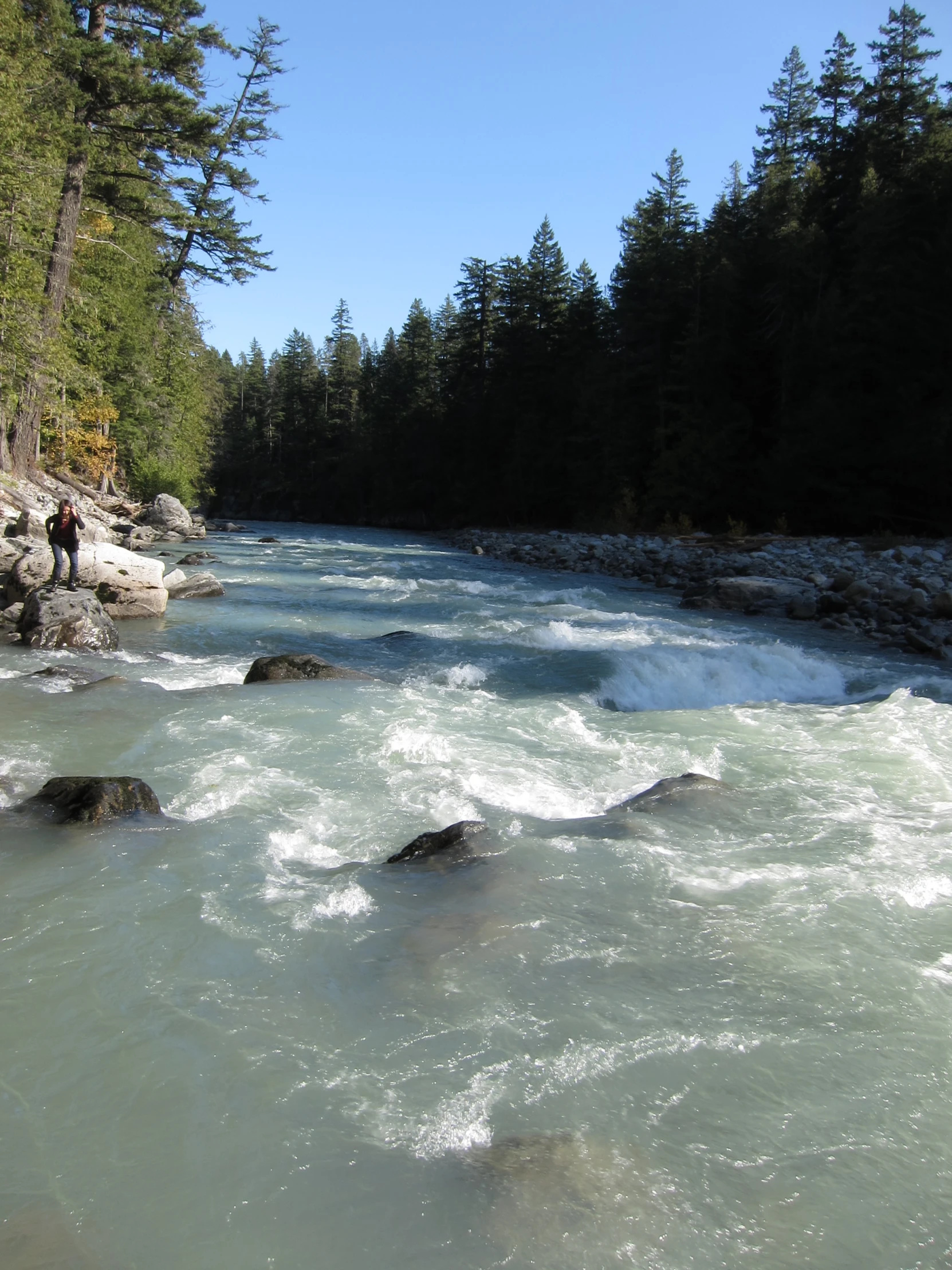 people stand by the shore of a river