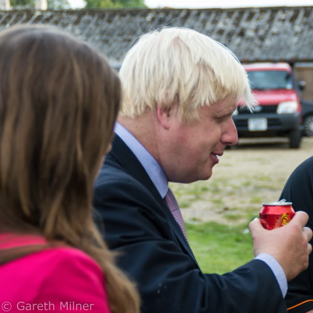 two people talking outside while the man has a cup