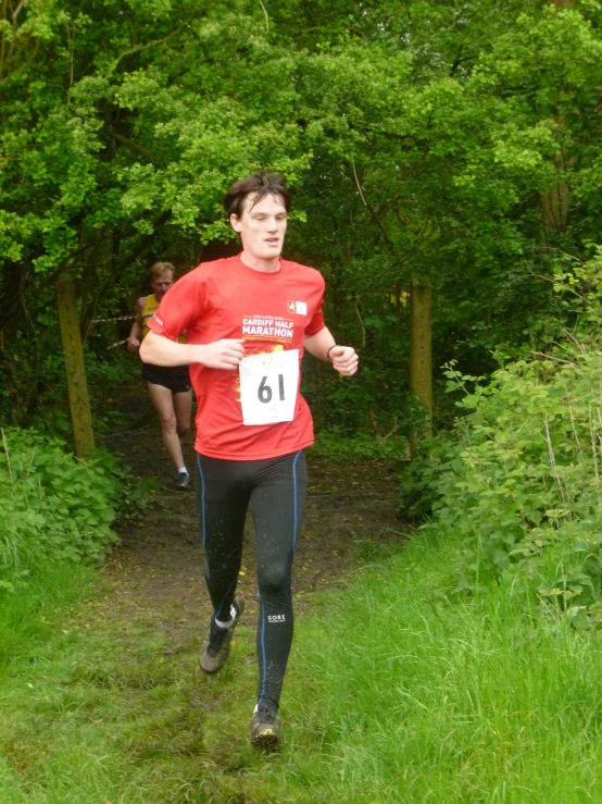 man wearing red shirt running down a path