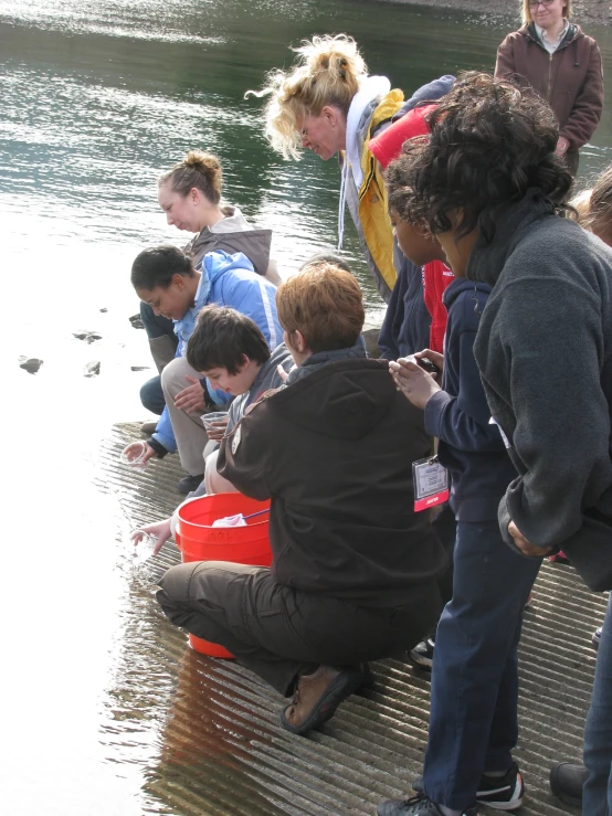 people sitting around on the ground beside the water