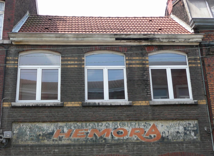 a brick building with multiple windows and faded words on the front
