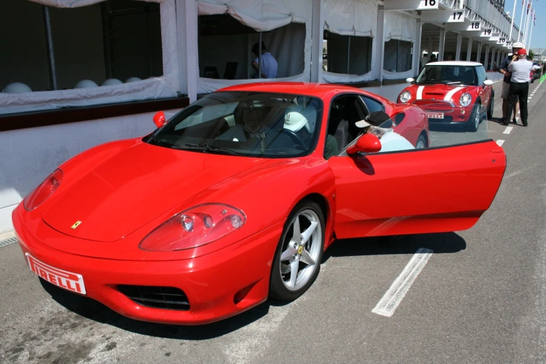 red ferrari parked by white cars in front of white building