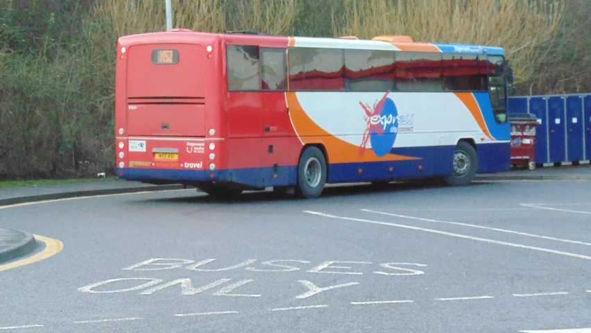 the double decker bus drives down the road