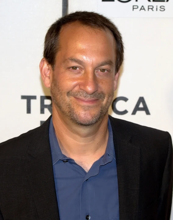 a man smiles for the camera while wearing a blue shirt